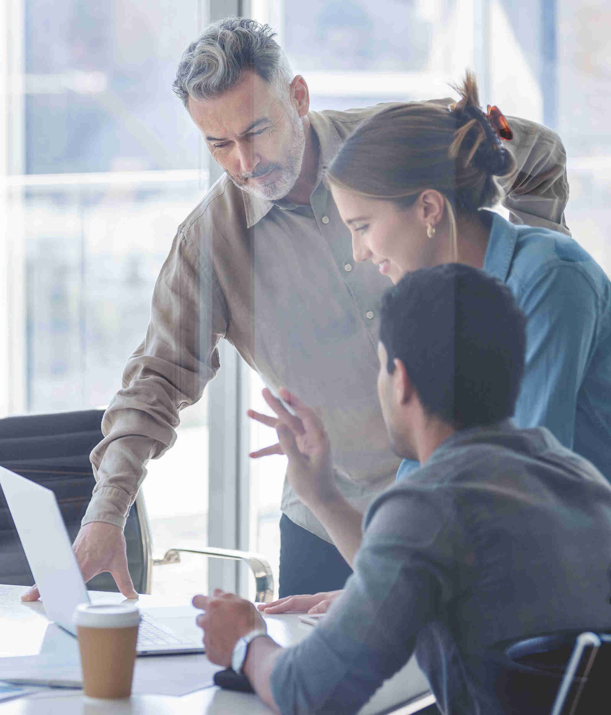 Three people are working in a bright office and have a lively exchange of ideas.