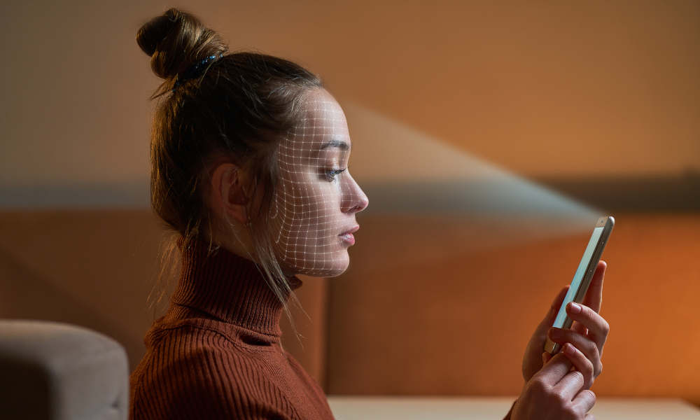 Stimmungsbild: Die Frau scannt das Gesicht mit einem Gesichtserkennungssystem auf dem Smartphone zur biometrischen Identifizierung.