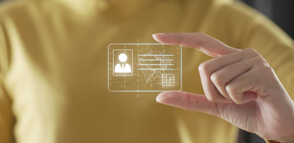 Montage: A person holds the icon of a digital ID card between their index finger and thumb and presents it to the camera.