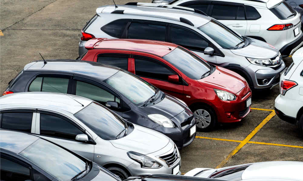 Mehrere Fahrzeuge verschiedener Marken und Farben auf einem Parkplatz, fotografiert aus der Vogelperspektive.