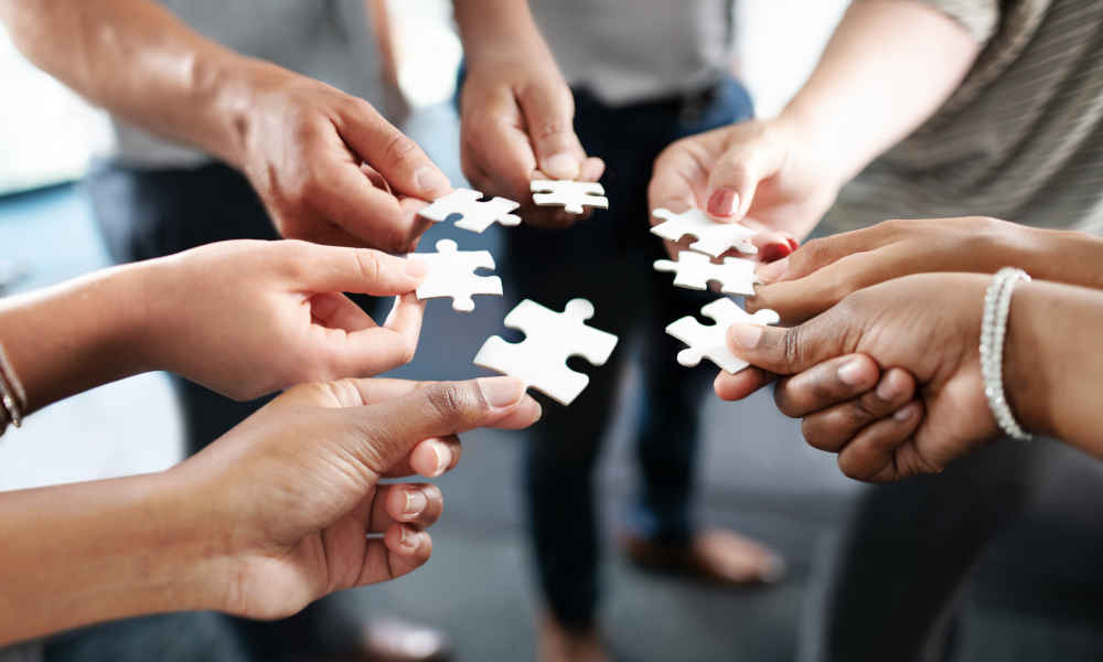 Hands bringing the jigsaw pieces together in the middle