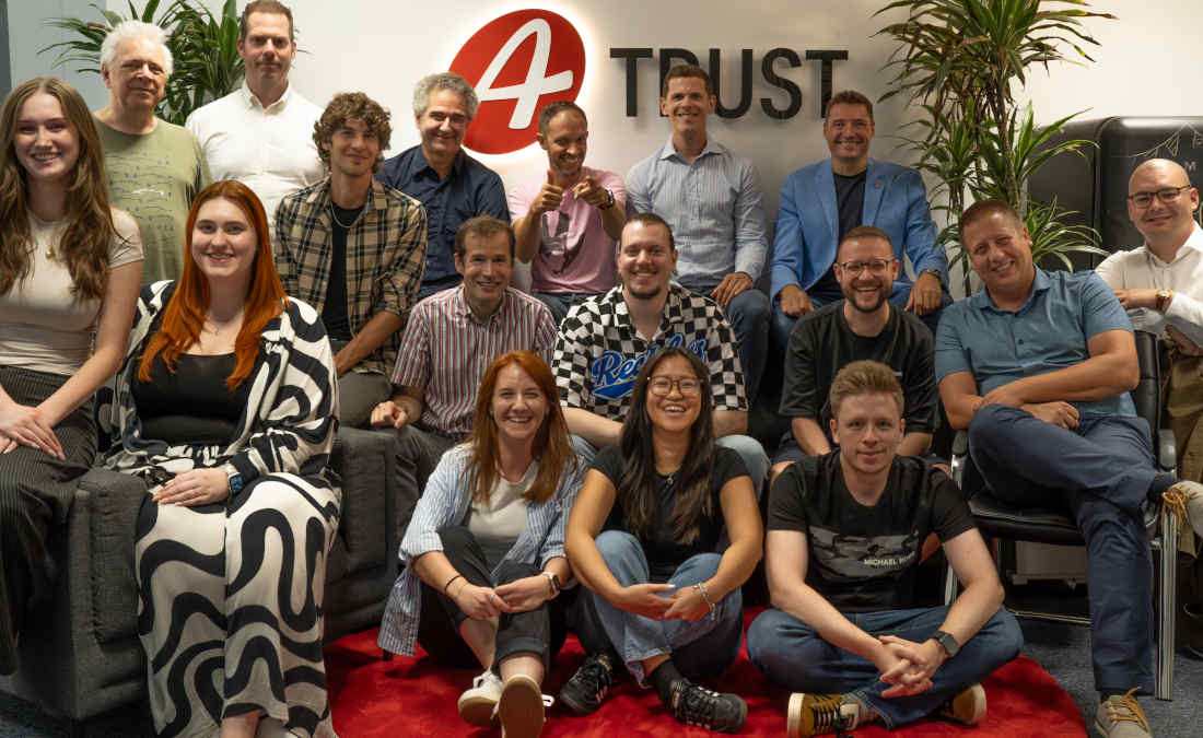 Strahlende Gesichter beim Mitarbeiter:innen Gruppenfoto im Foyer von A-Trust